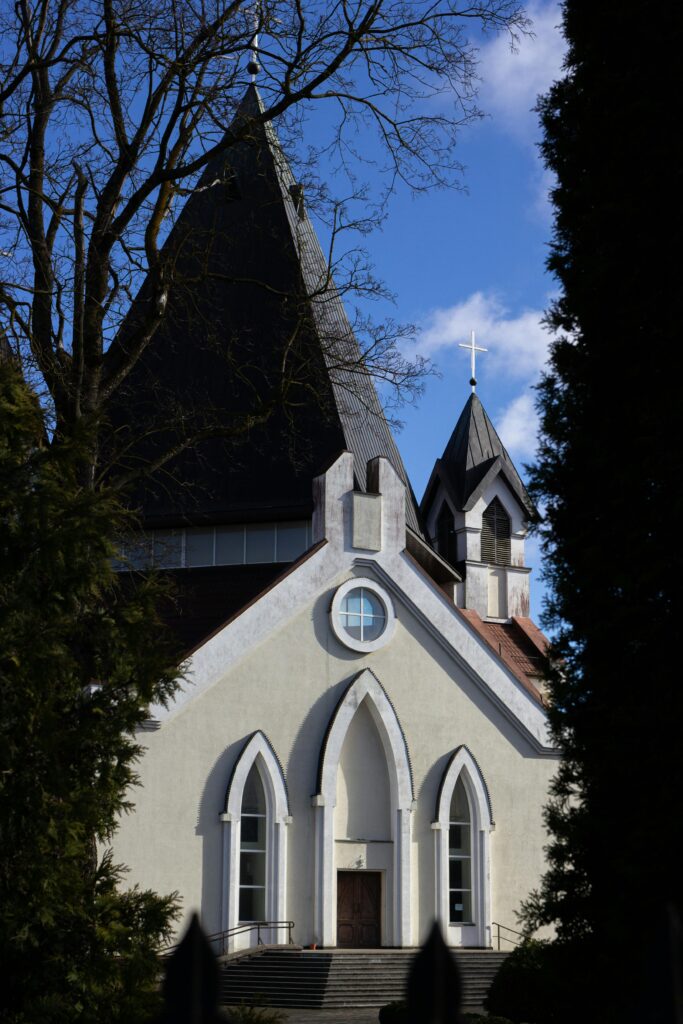 pexels-photo-9808949-9808949 A beautiful Gothic style church exterior under a clear blue sky, surrounded by trees.
